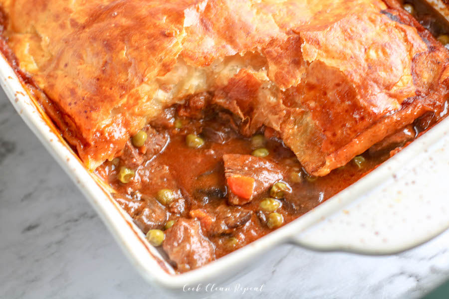 A pan of beef pot pie with a scoop missing.