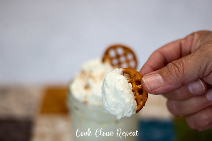 A scoop of the dip on a pretzel ready to be enjoyed.