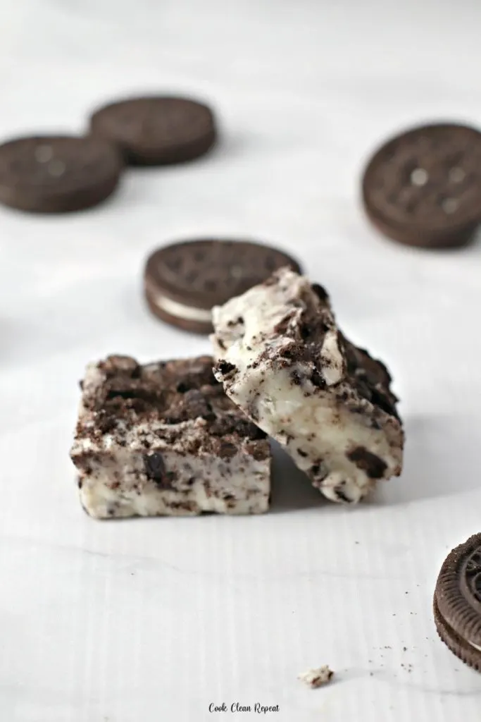 Two pieces of finished Oreo fudge with cookies in the background. 