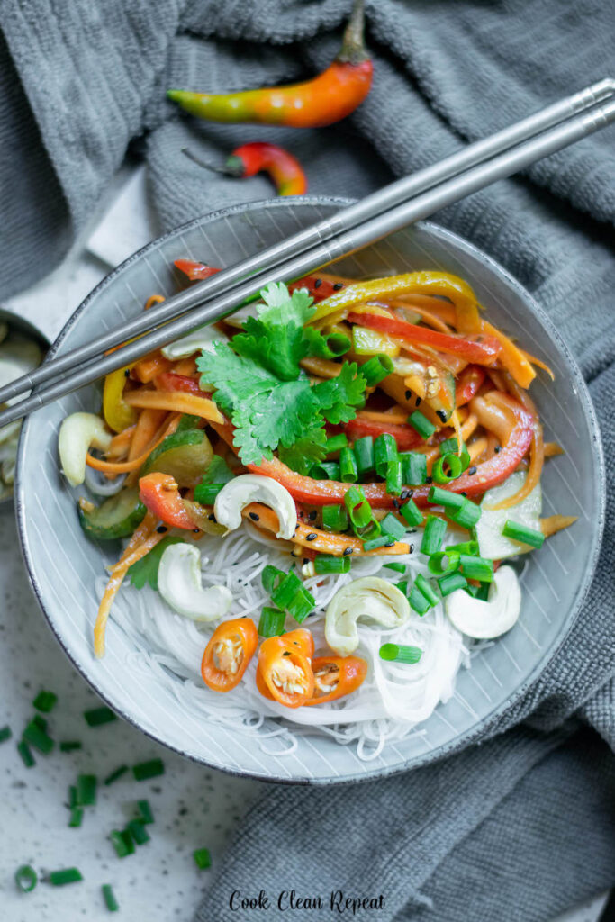 This photo shows the rice noodles topped with veggies and other fixings and ready to be tossed with dressing and eaten. 