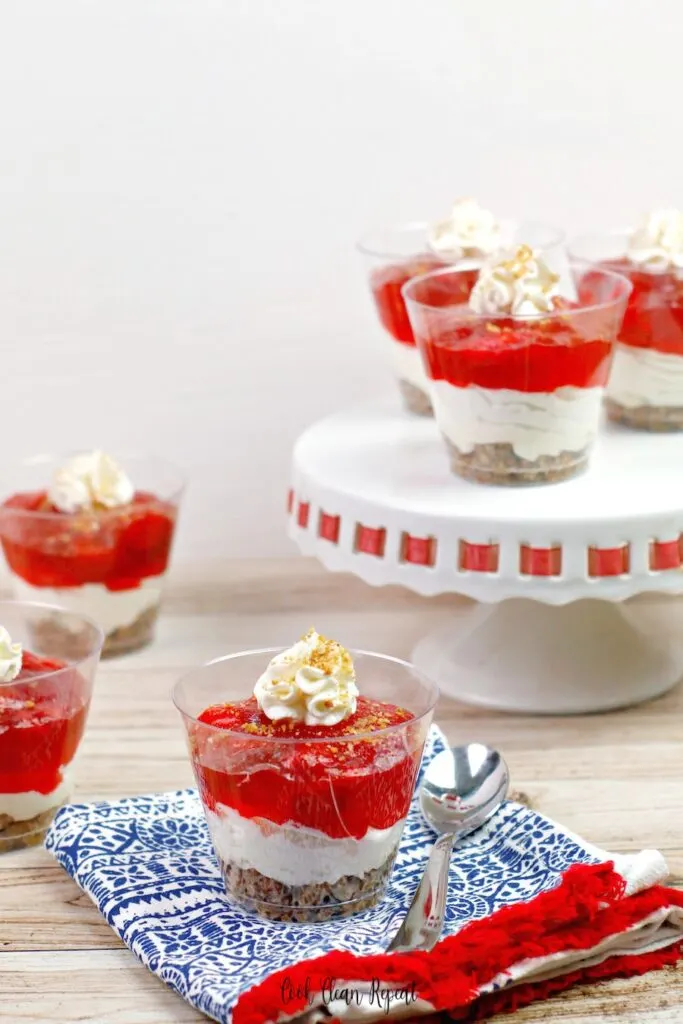 Here we see a variety of strawberry jello cheesecake cups set out and ready to be served. 