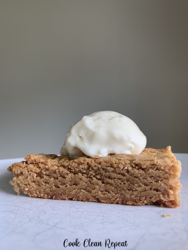 A close up view of the finished blondies on a plate ready to eat with ice cream on top.