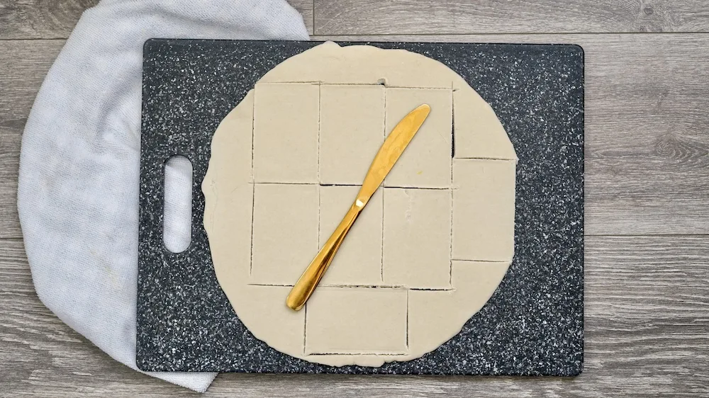 Dough being cut out into squares. 