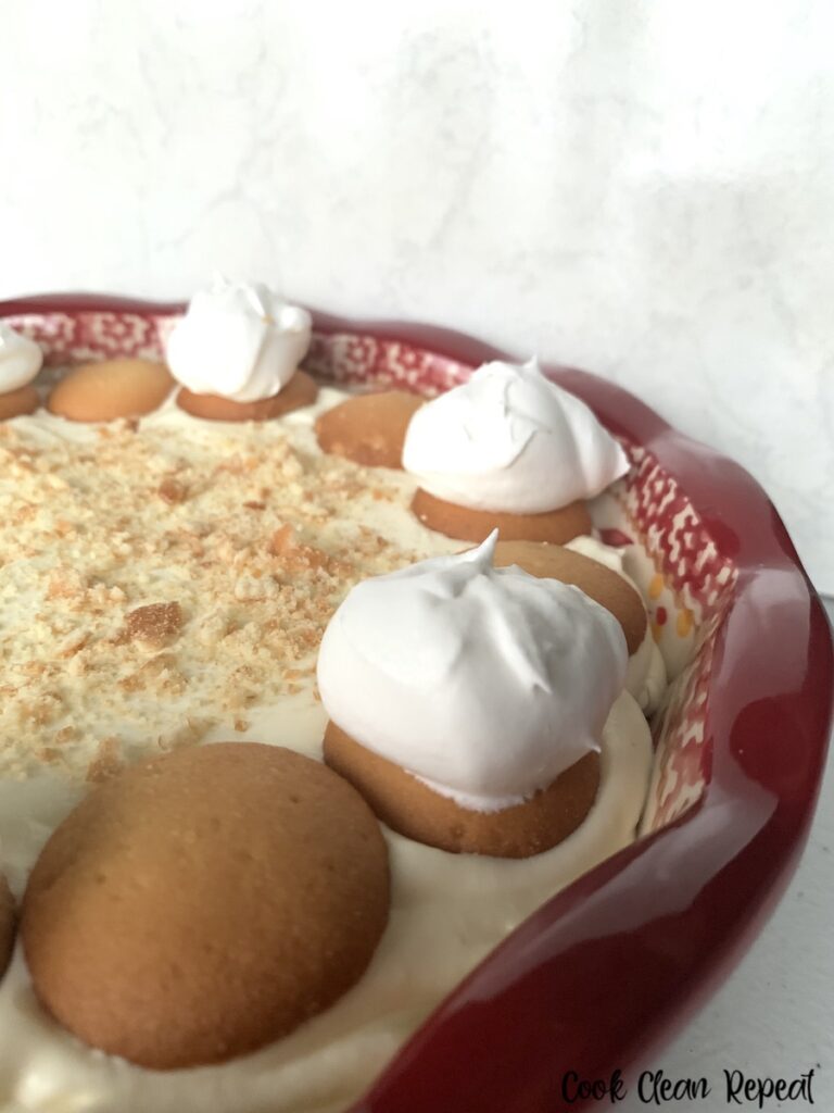 A close up of the finished banana pudding dip topped with Nilla wafers and dollops of whipped cream. 
