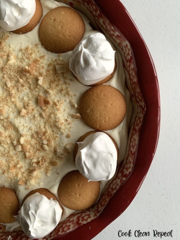 Half the pan of the dip shown topped with cookies and whipped cream. 