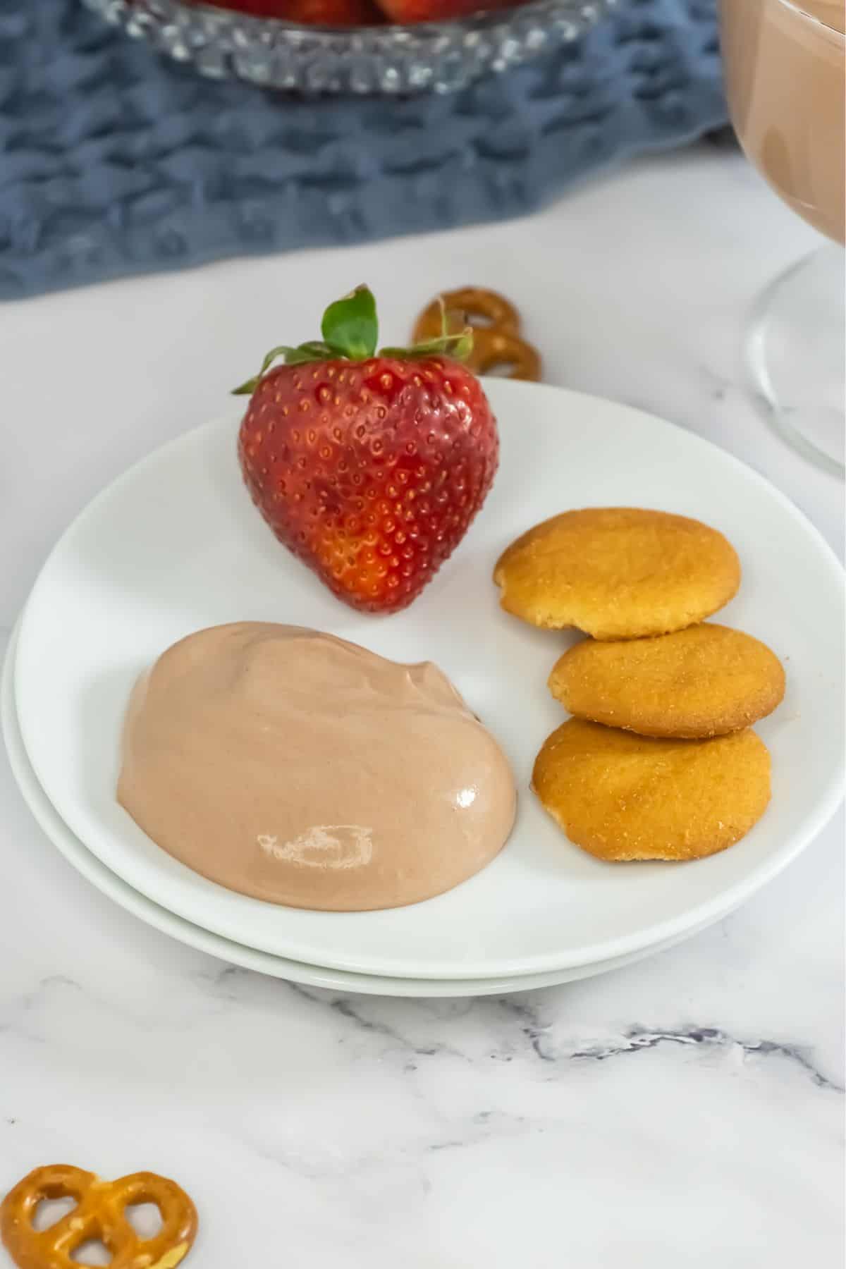 A plate with a strawberry, vanilla cookies and chocolate dip.