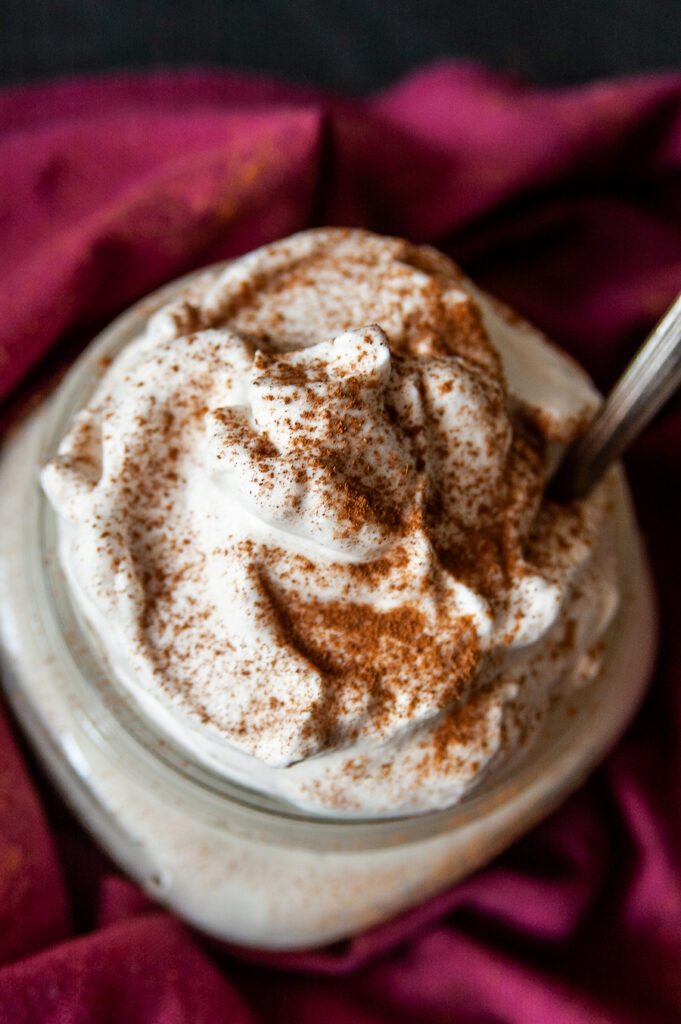 A top down look at a container full of the homemade cinnamon whipped cream topping. 