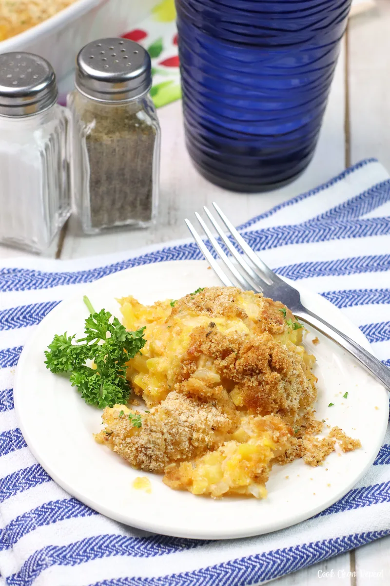 yellow squash casserole on white plate with a fork