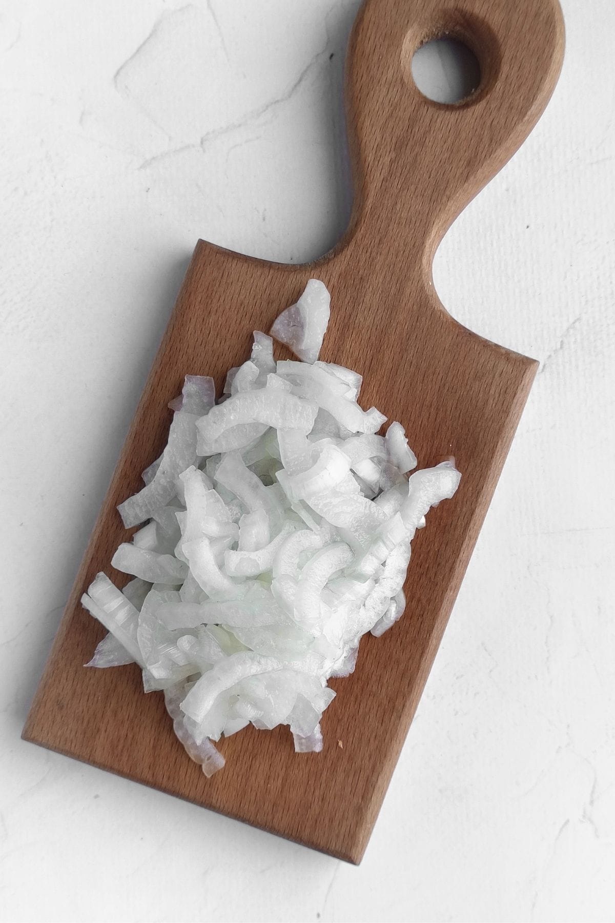 Onion chopped up on a wooden cutting board.