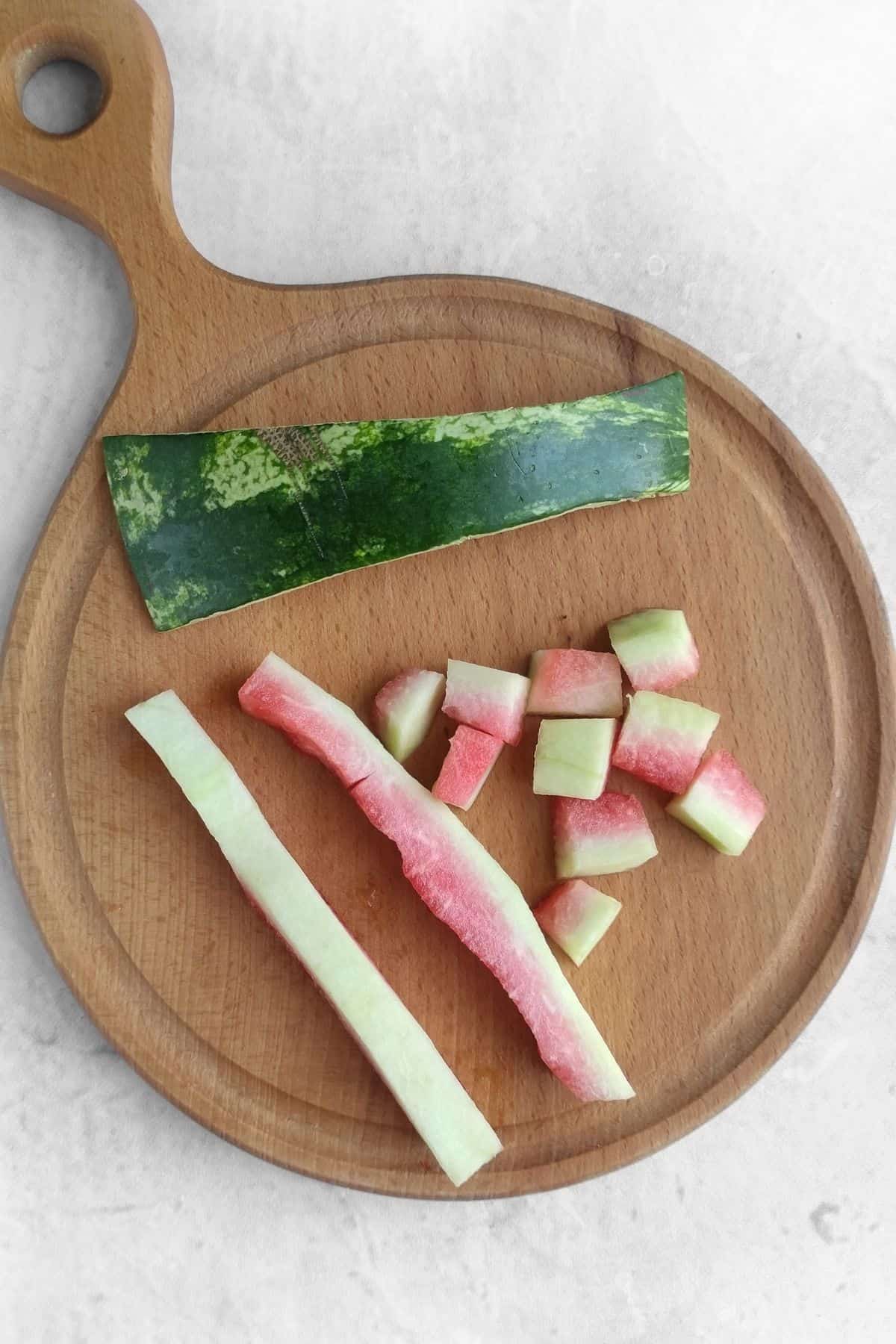 Watermelon being cut up on a wooden cutting board.