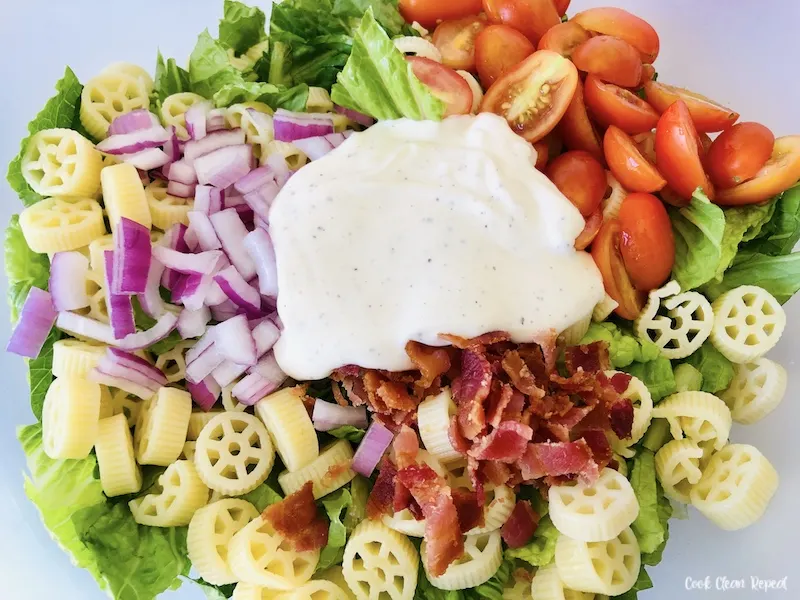 Salad with pasta and dressing ready to be mixed. 
