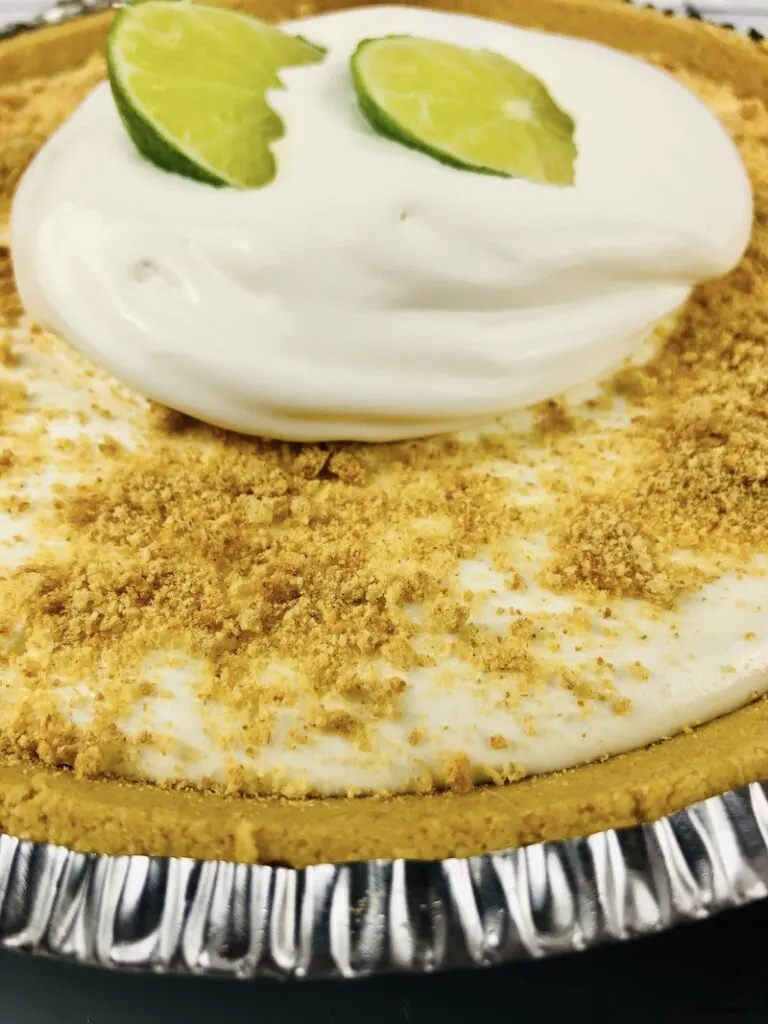 Full finished pie topped with graham crackers and whipped cream with limes. 