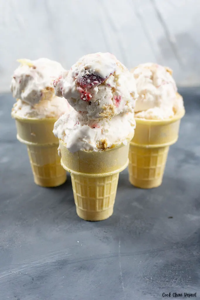 A look at the finished ice cream with strawberries and graham crackers scooped into cones ready to serve. 