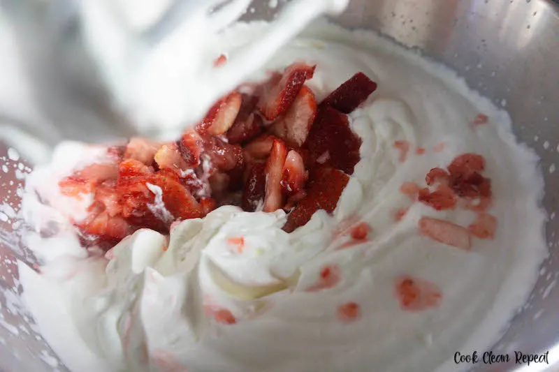 strawberries and condensed milk being folded into the mixture. 
