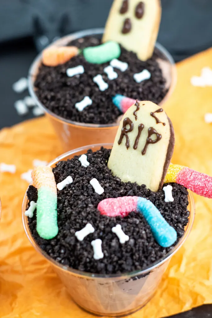 Decorating with worms and grave stone cookies for the final touches on the halloween dirt pudding dessert. 