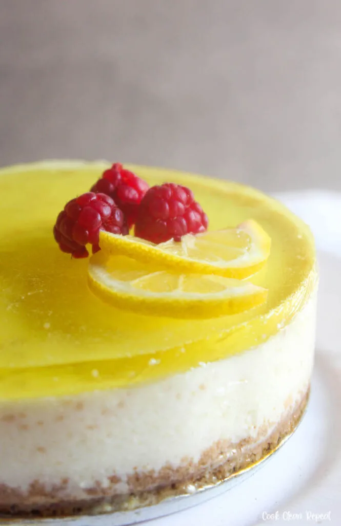 close up view of the finished lemon cheesecake topped with lemons and raspberries.
