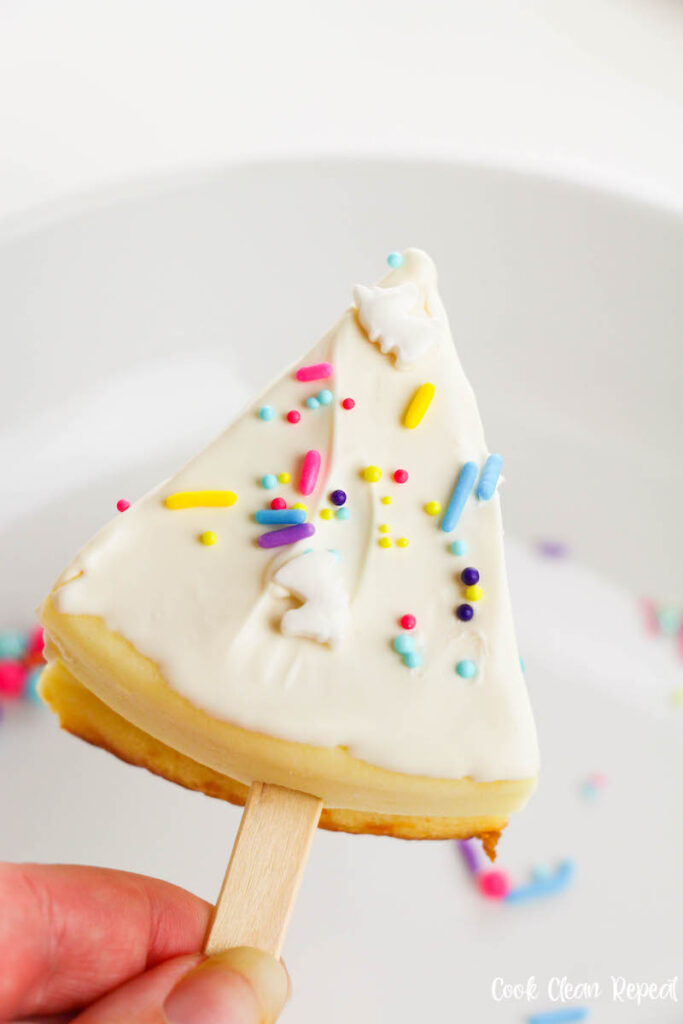 cheesecakes on a sticks being sprinkled with unicorn sprinkles. 