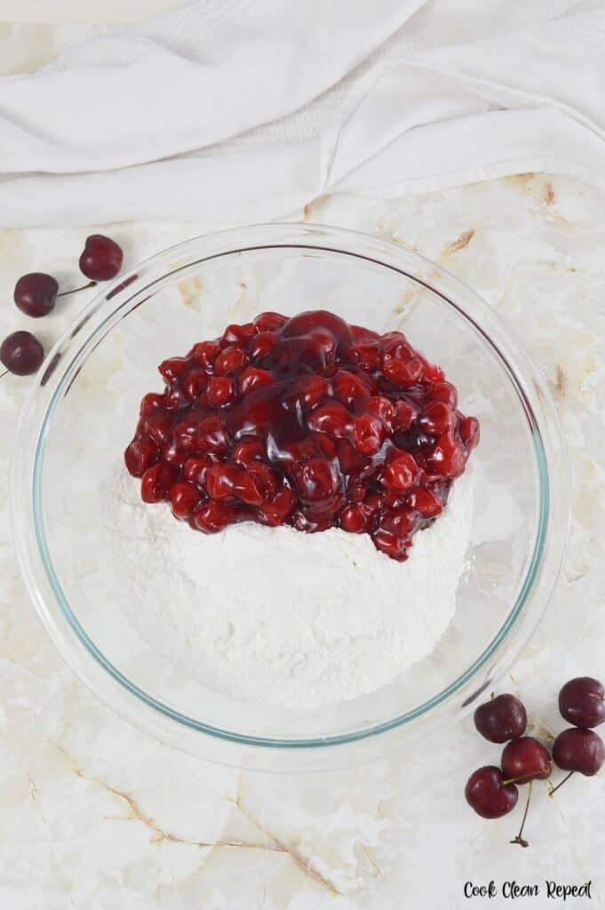 cherry pie filling and cake mix in a mixing bowl.