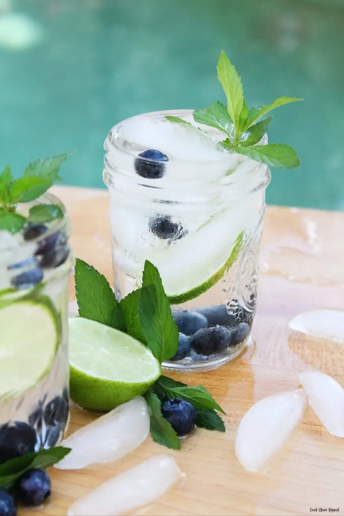 A look at a glass of the finished infused water recipe with blueberries and lime with mint. 