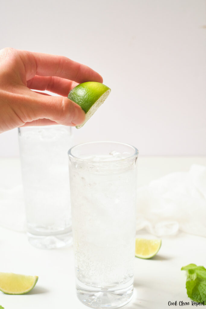 lime being squeezed into the sparkling water glasses. 