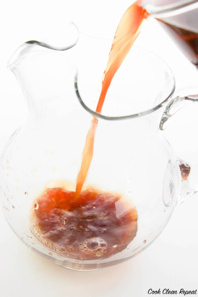 cooled tea being poured into an empty glass pitcher