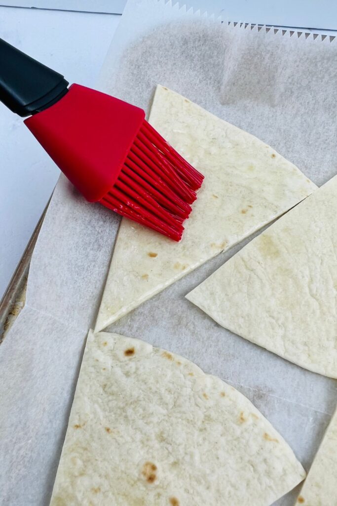 brushing butter onto tortilla triangles