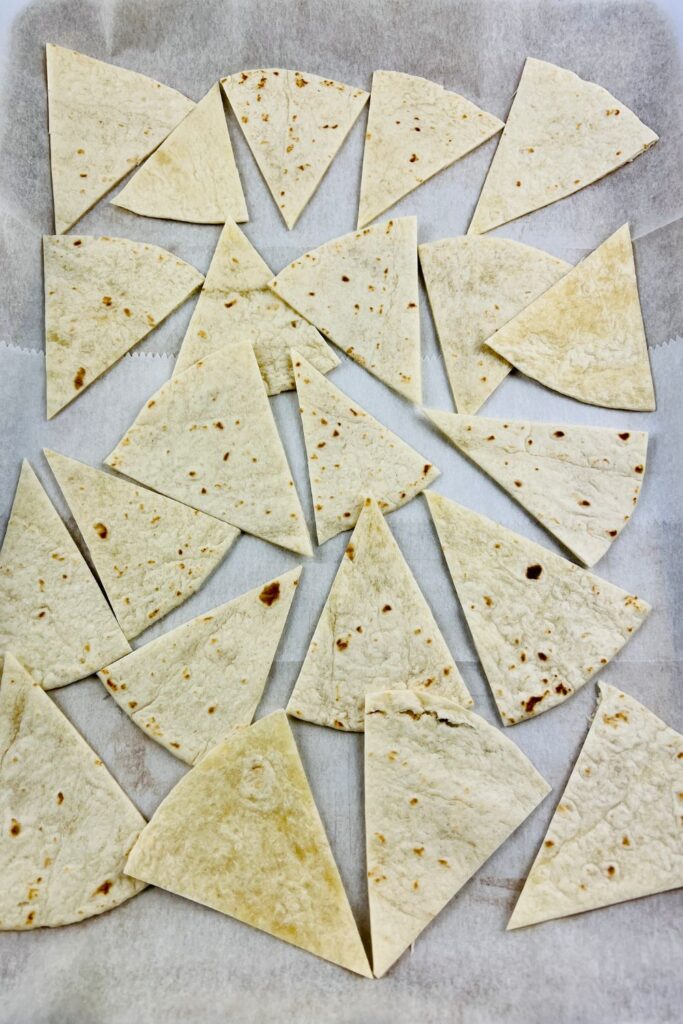 tortilla triangles on a baking sheet with parchment paper