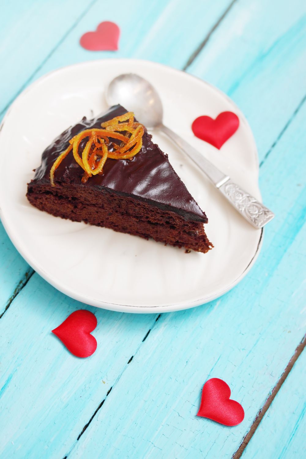 chocolate cake slice on a plate with hearts around it