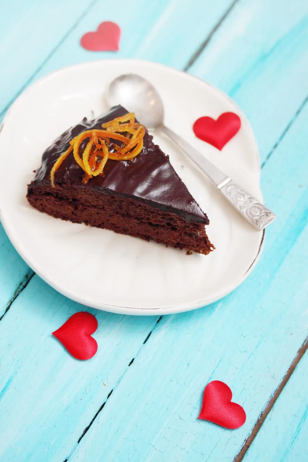 chocolate cake slice on a plate with hearts around it
