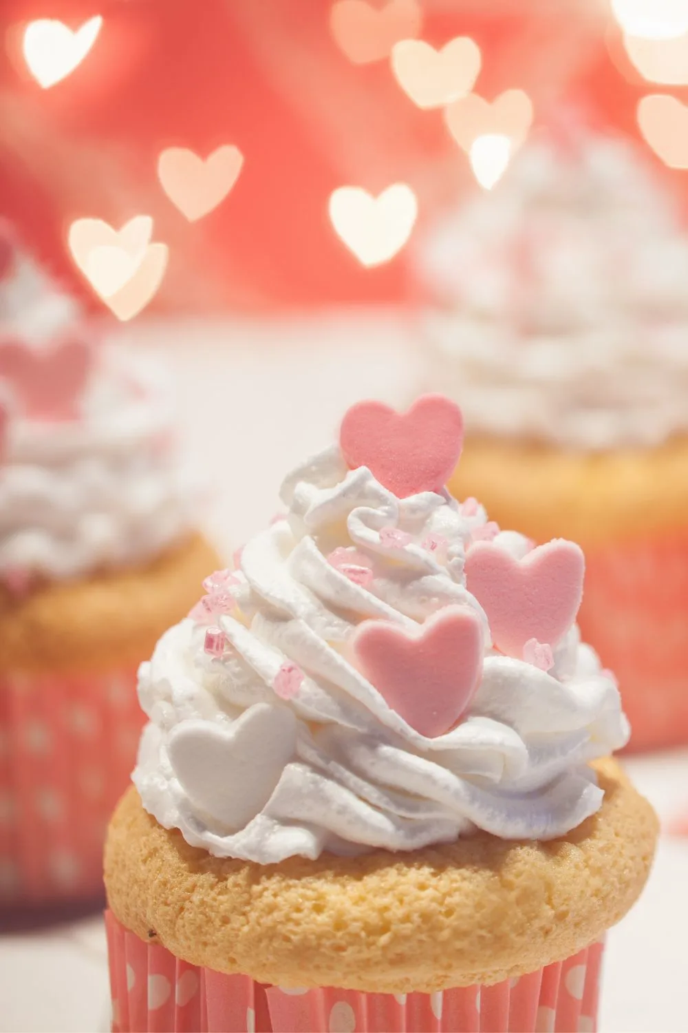 vanilla cupcakes with pink hearts on the icing