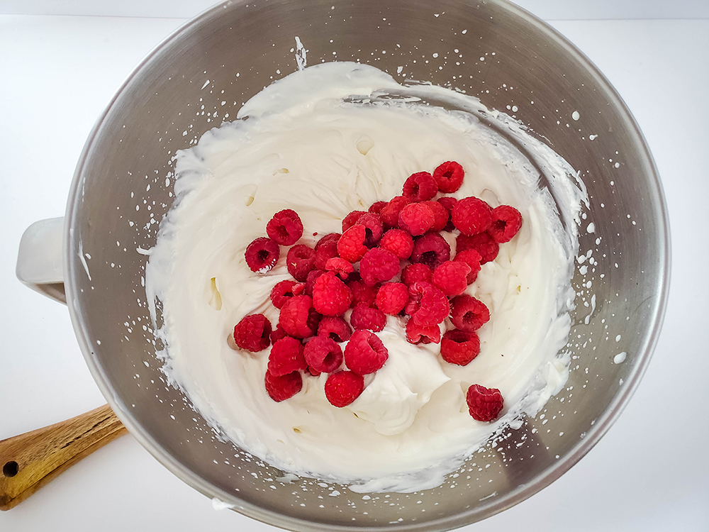 An overhead view of raspberries being included with the other no churn ice cream ingredients.