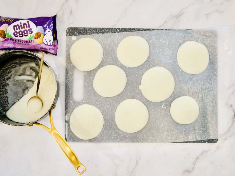 white chocolate being poured on a baking sheet in circles