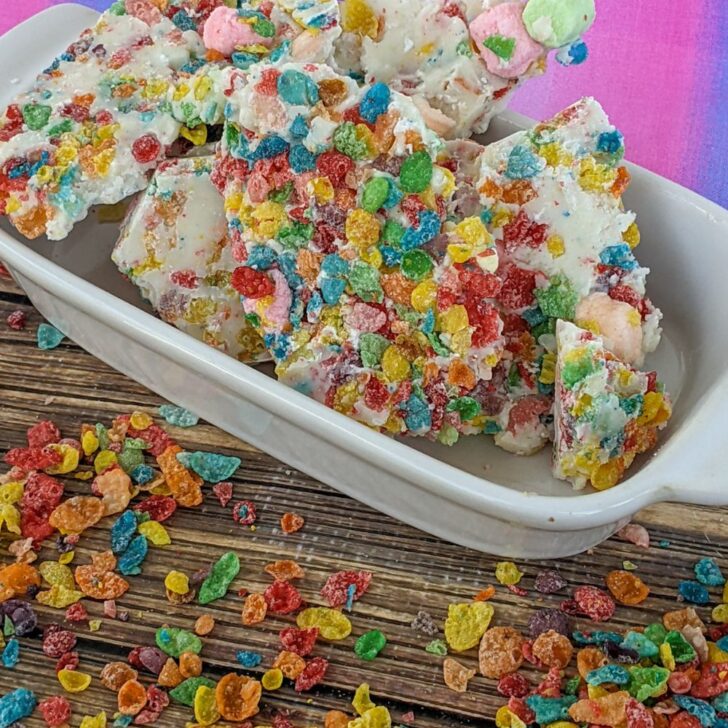 fruity pebble rainbow bark sitting in a white dish with a pink and purple background