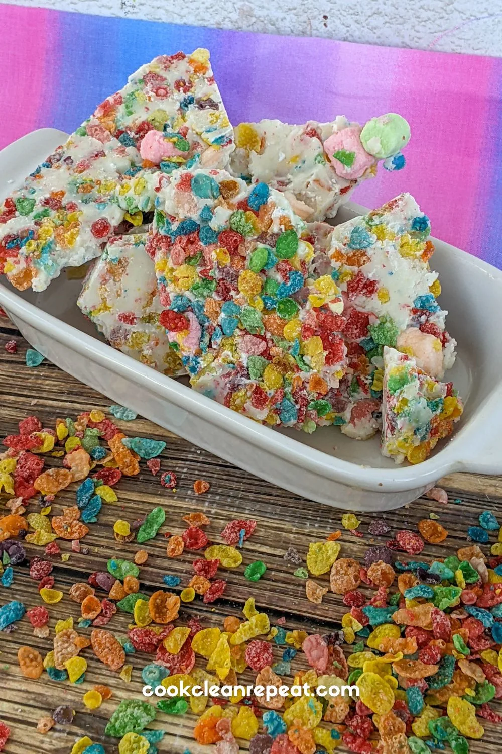 fruity pebble rainbow bark sitting in a white dish with a pink and purple background