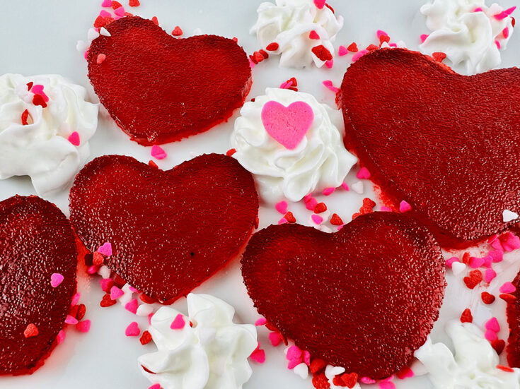 completed Valentine's Day jello jigglers on a white plate with sprinkles and whipped cream
