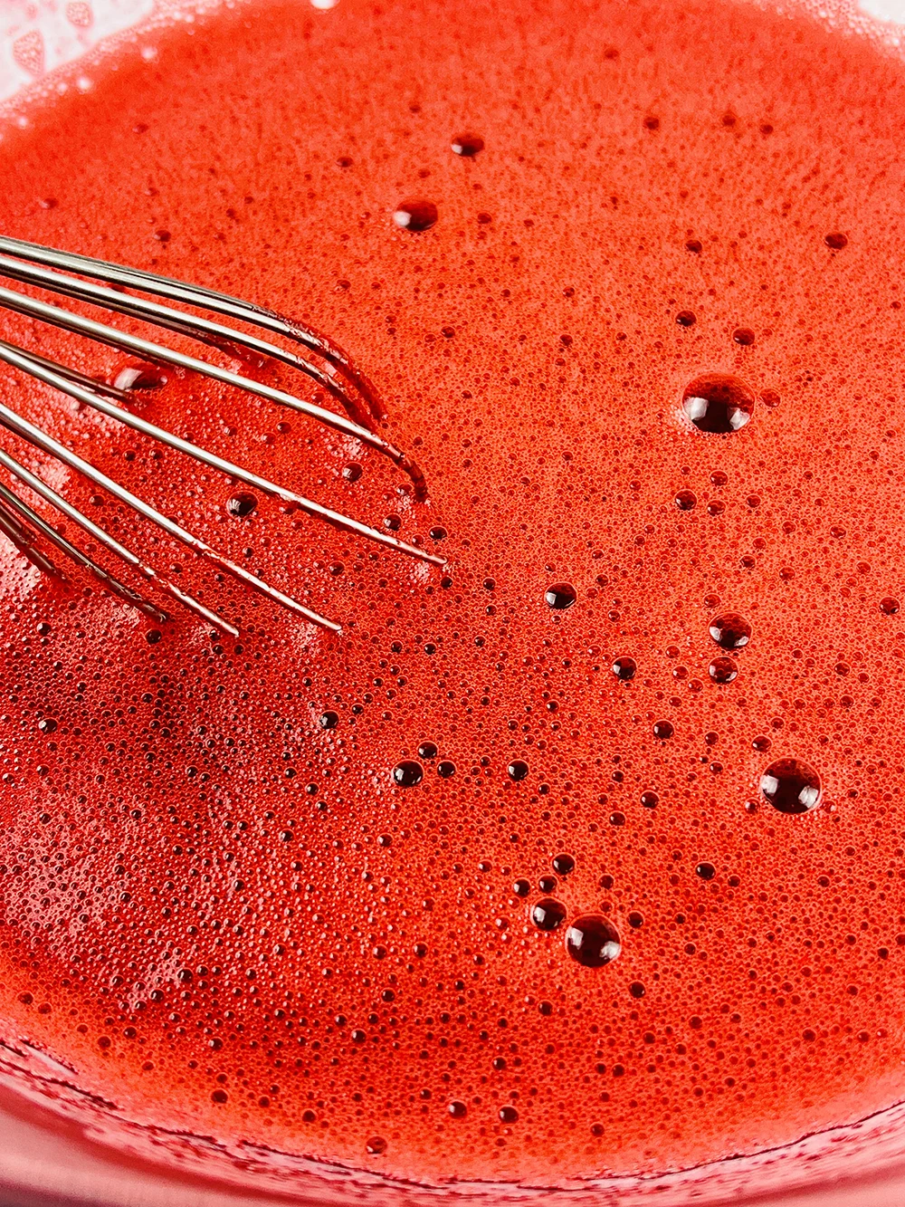 red mixture in a bowl with a whisk