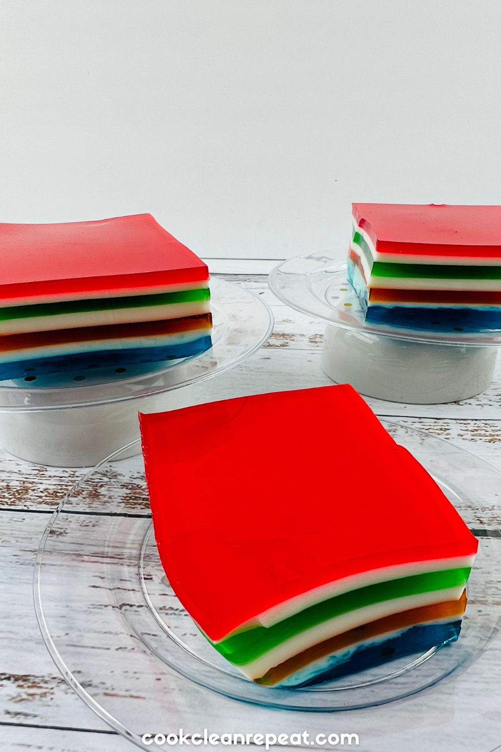 three slices of jello ribbon salad sitting on dessert platters