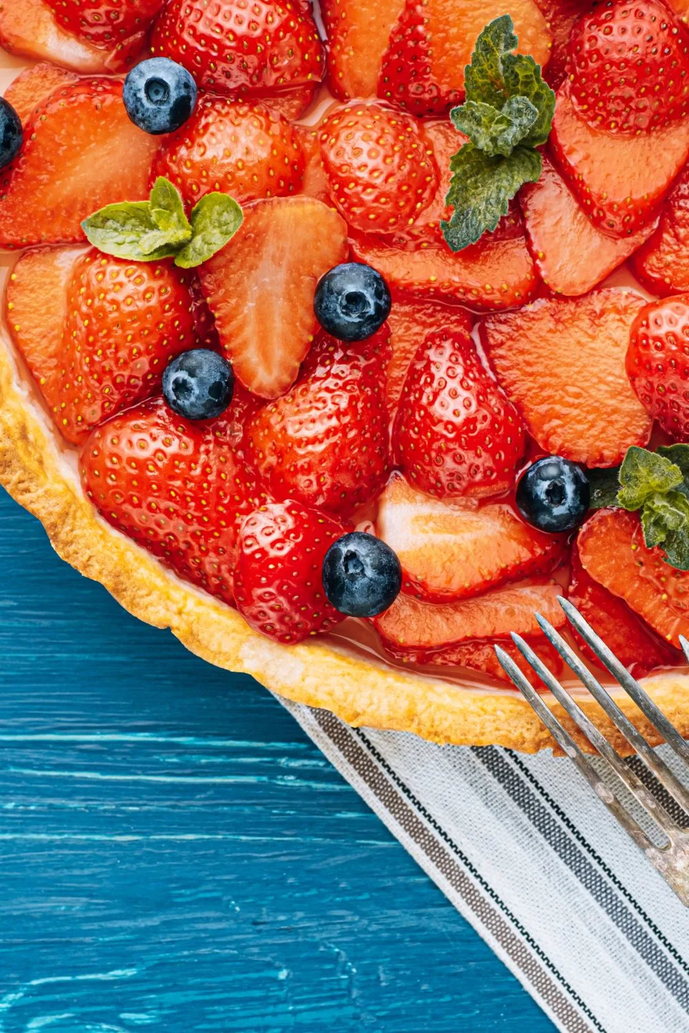 strawberry pie with blueberries and mint garnished on top