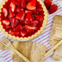 strawberry pie with jello in a pie pan on a red and white striped dish towel