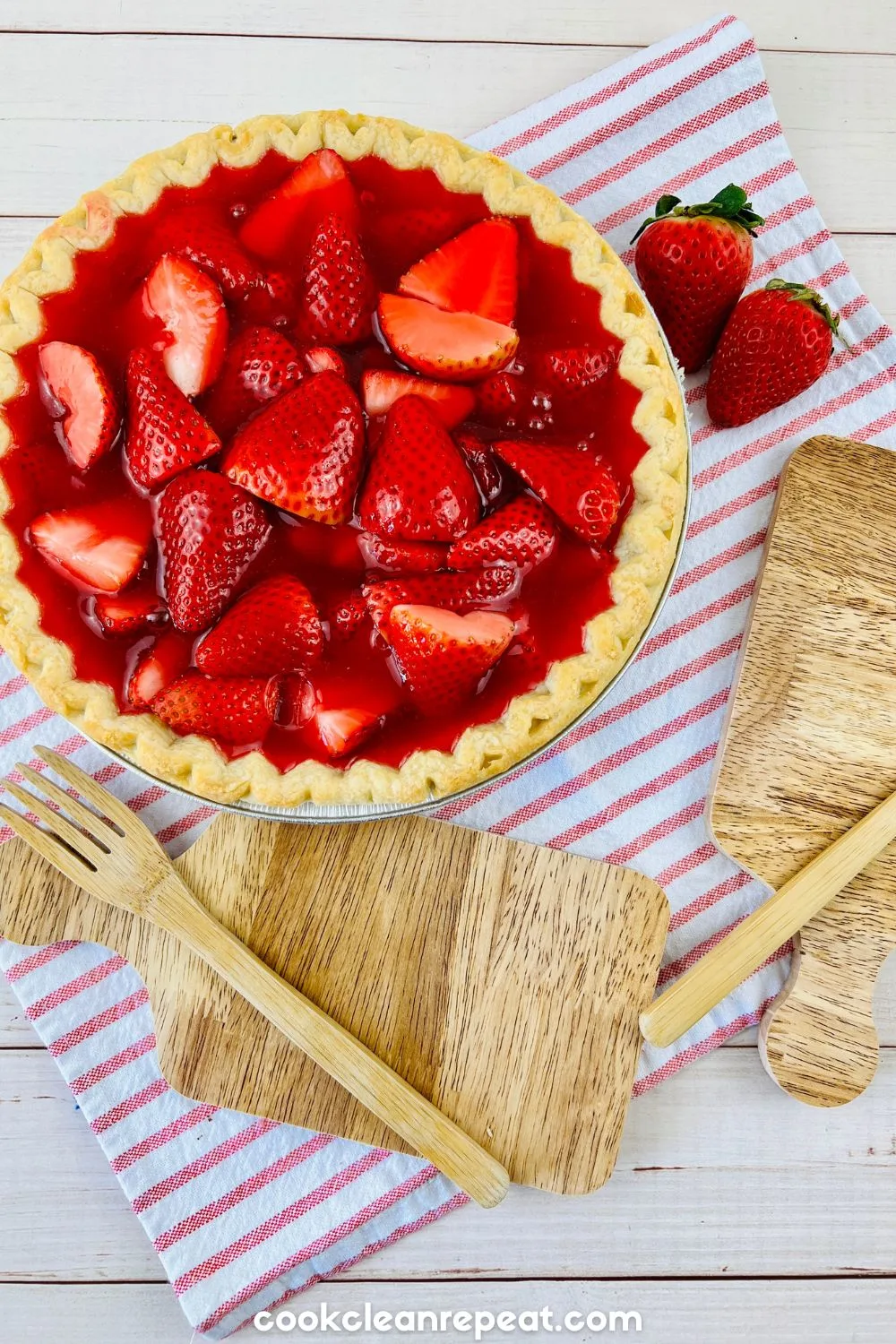 strawberry pie with jello in a pie pan on a red and white striped dish towel