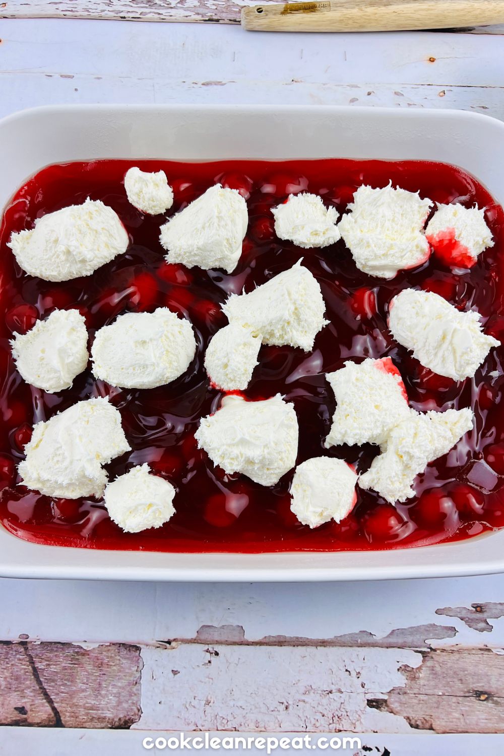 cherry filling in a baking dish with cream cheese scooped on top