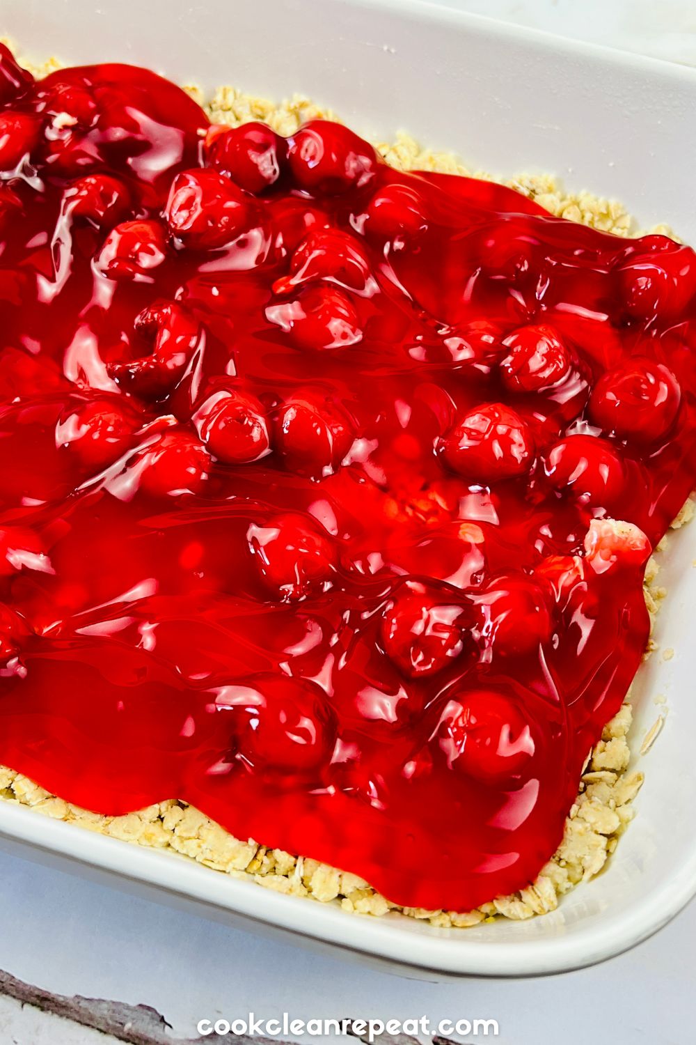 canned cherry pie filling on top of oats in a baking dish