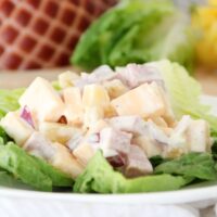 Pineapple Ham Salad on a lettuce leave with baked ham in the background