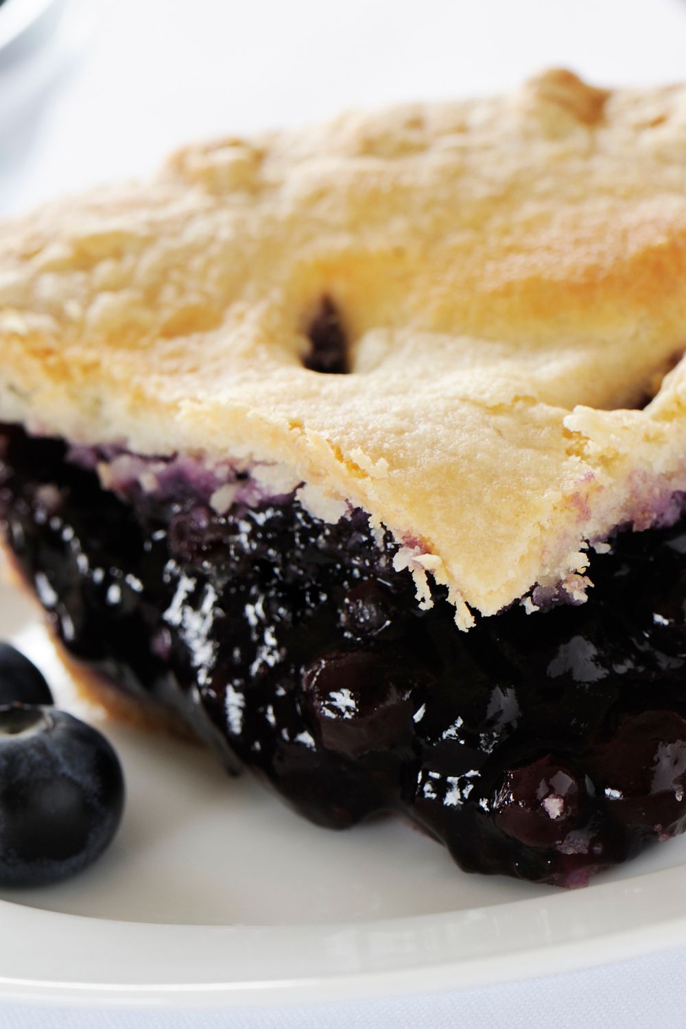 an up close picture of a slice of blueberry pie filled up