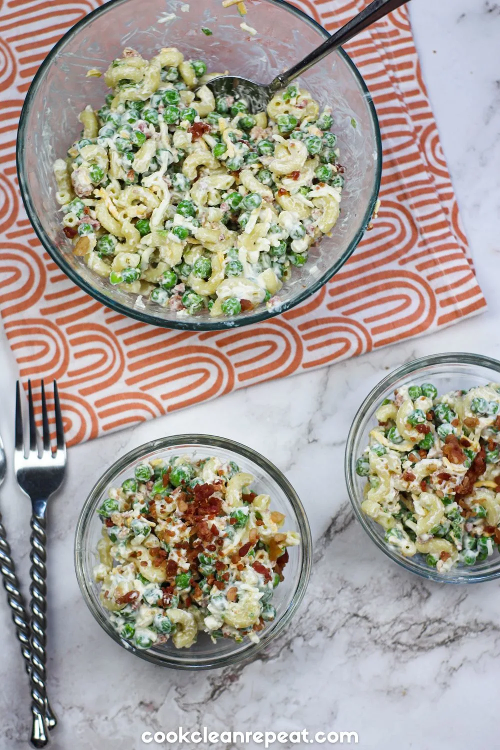 two small bowls of pea and pasta salad with the larger bowl of the whole mix above them