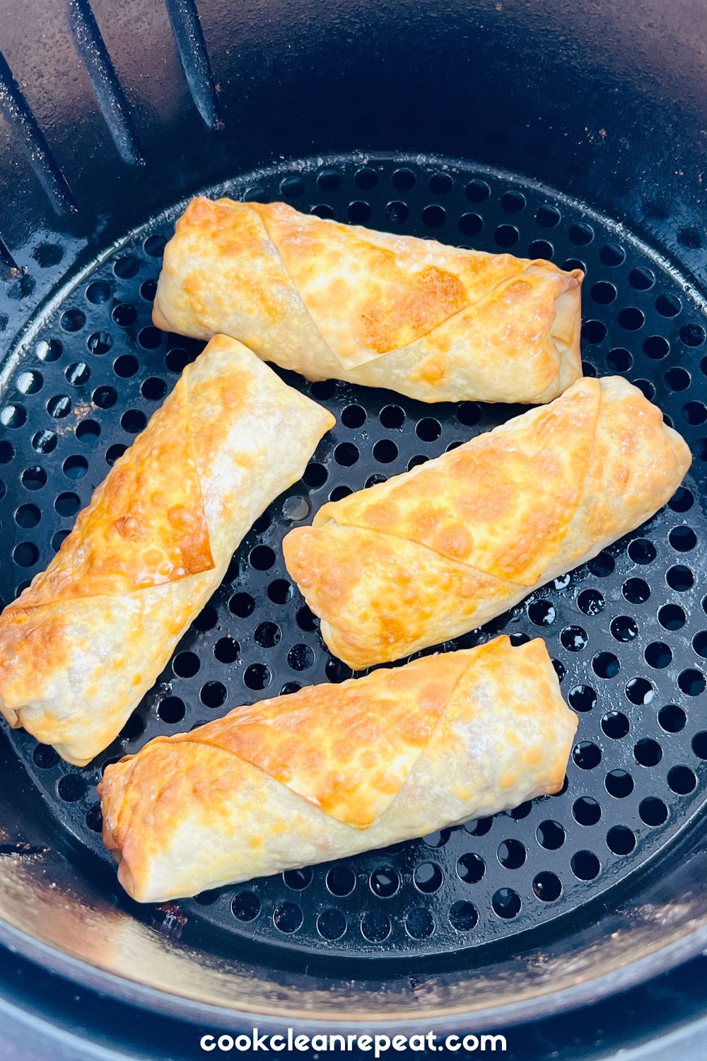 four egg rolls sitting in an air fryer