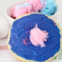 cookie covered with blue icing and a pink piece of cotton candy on top