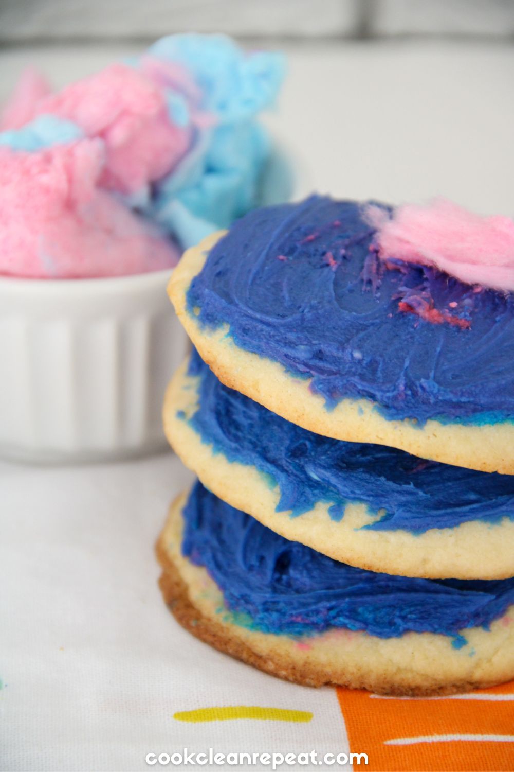 three cookies stacked on top of each other with cotton candy behind them