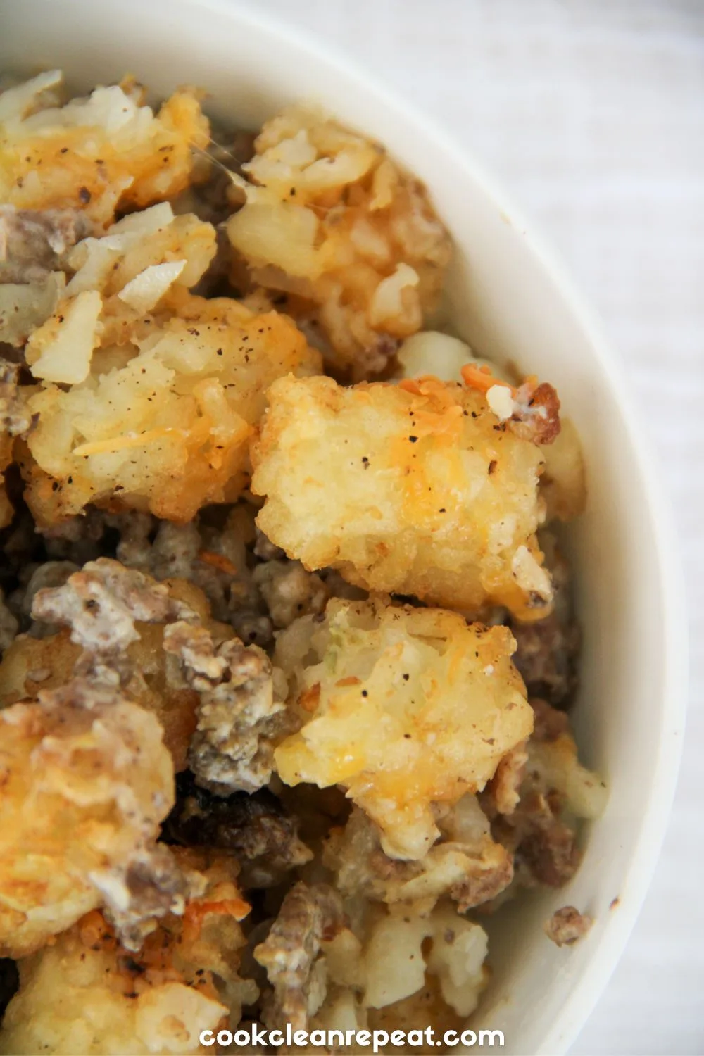 half of a tater tot casserole in a white bowl