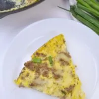 a sliced piece of yellow squash quiche on a white plate
